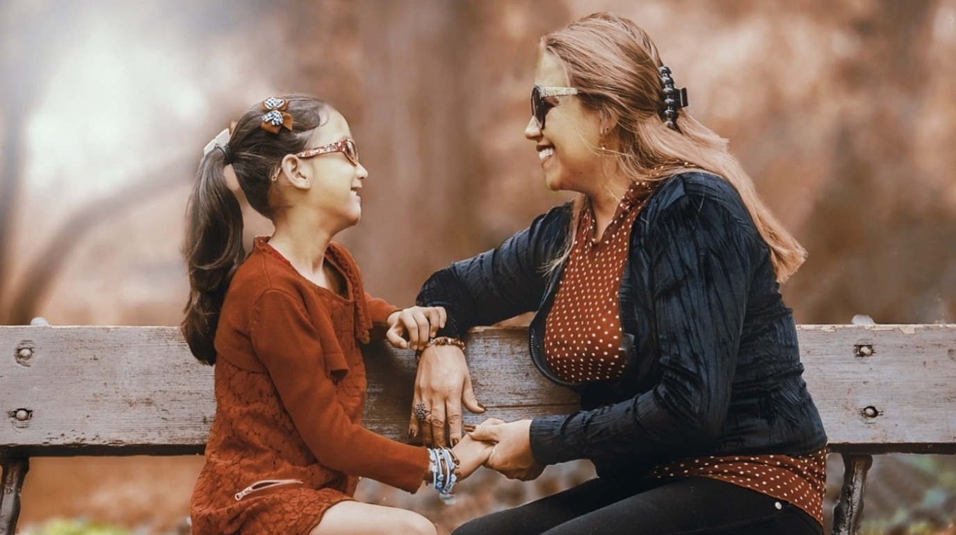 Mother and daughter sitting on a park bench